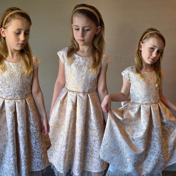 Alt tekst:
Luxe meisjesjurk in champagnekleur met bloemenstructuur en transparante tule zoom uit de Petite Occasion Dresses collectie van Jacobsz Atelier.